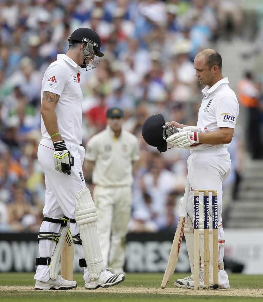 England's Jonathan Trott, right, holds his helmet as he talks to teammate Kevin Pietersen after his helmet sustained damage from a ball bowled by Australia's Ryan Harris during play on the third day of the fifth Ashes cricket Test at the Oval cricket ground in London.