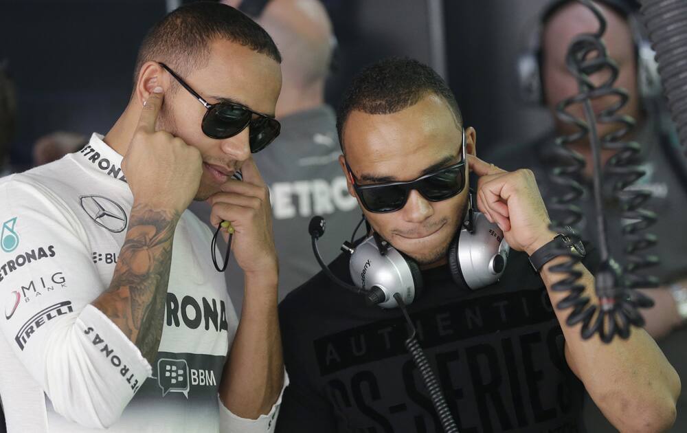 Mercedes driver Lewis Hamilton of Britain shows his brother Nicolas his car during the first practice session at the Indian Formula One Grand Prix at the Buddh International Circuit in Noida.