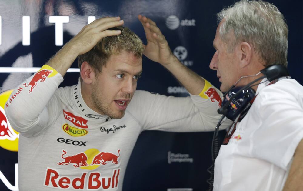 Red Bull driver Sebastian Vettel of Germany gestures as he talks with team advisor Helmet Marko during the first practice session at the Indian Formula One Grand Prix at the Buddh International Circuit in Noida.