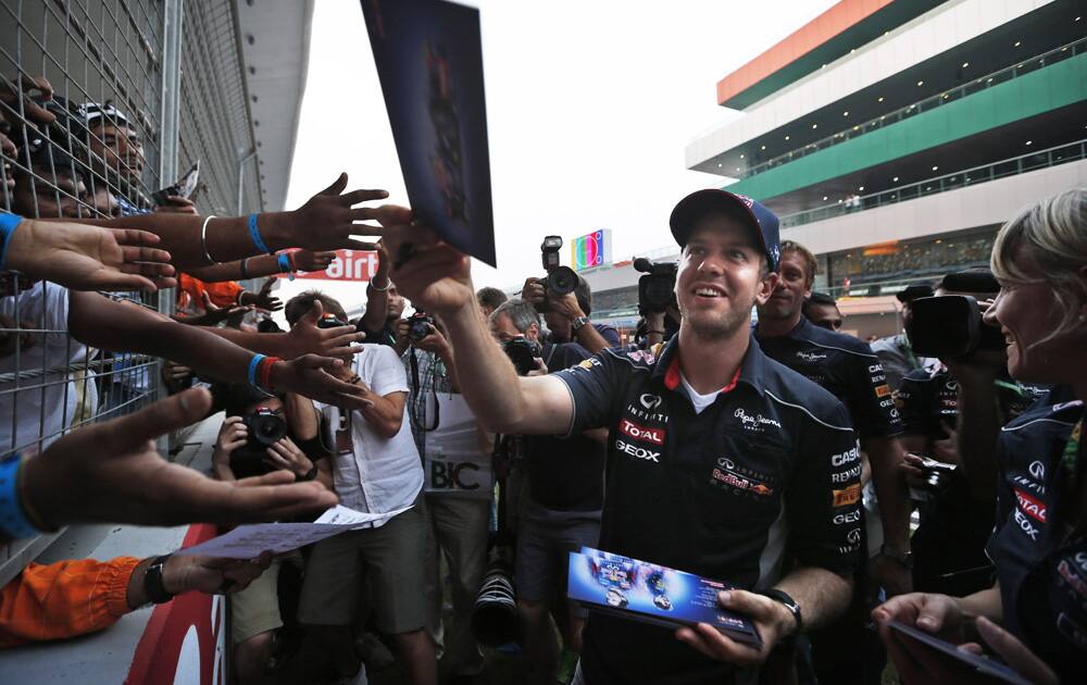 Red Bull driver Sebastian Vettel of Germany hands out signed copies of his photograph to fans ahead of the Indian Formula One Grand Prix at the Buddh International Circuit in Noida.