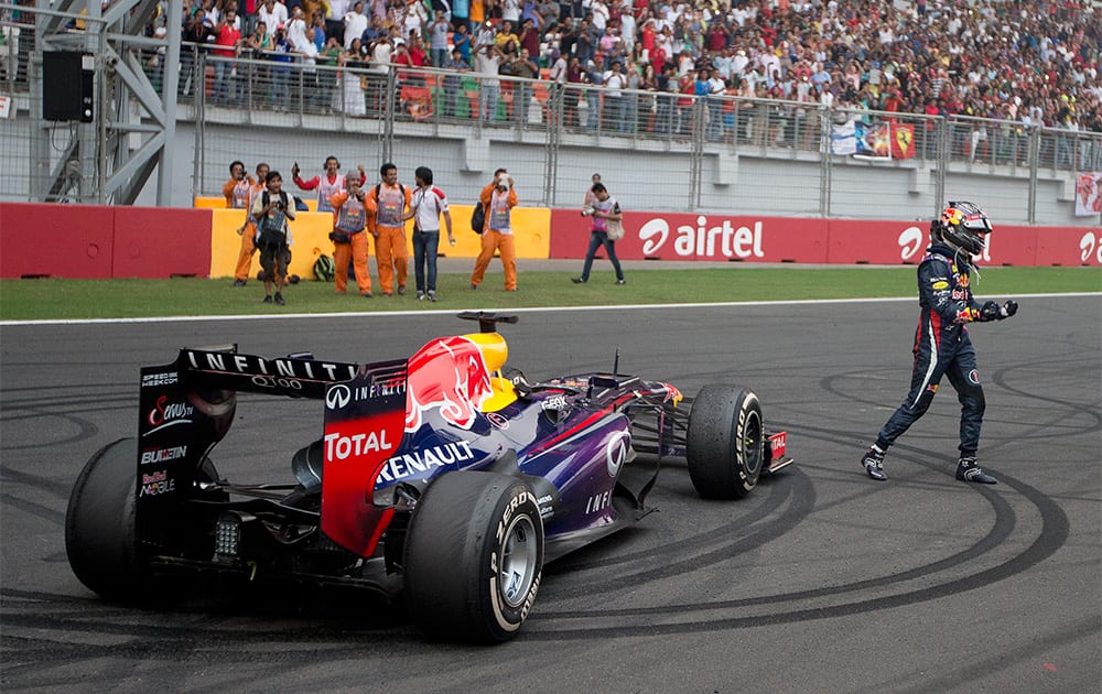 Red Bull driver Sebastian Vettel of Germany celebrates on the track after winning the Indian Formula One Grand Prix and his 4th straight F1 world championship at the Buddh International Circuit in Noida.