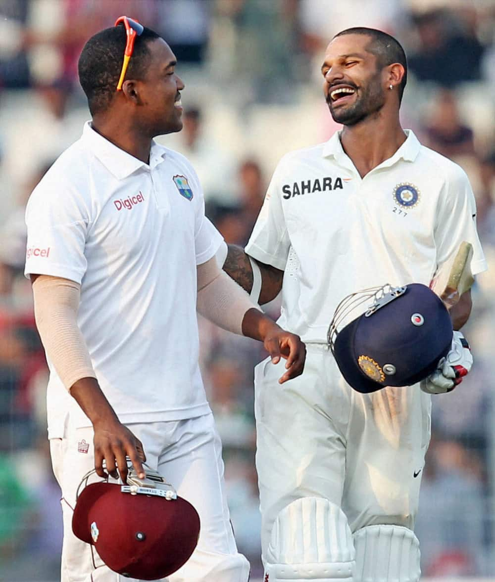 West Indies player D.Bravo shares a light moments with India's opener Shikhar Dhawan (R) at the close of first day of First Test Match at Eden Garden in Kolkata.