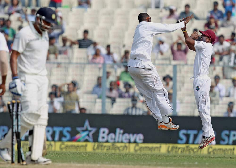 West Indies bowler Shane Shillingford celebrates with his teammate after dismissing Indian opener M Vijay on the second day of the first test match at Eden Garden in Kolkata.