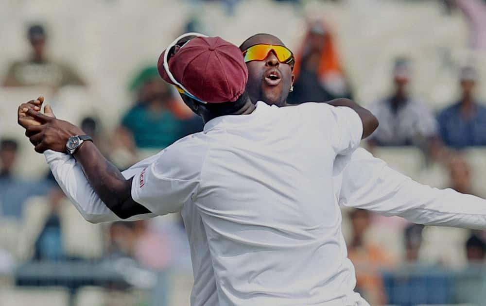 West Indies players Shane Shilingford and Darren Sammy celebrate on the 2nd day of the first test match in Kolkata.