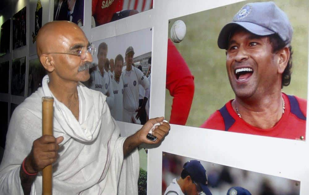 A fan of master blaster dressed as Mahatma Gandhi watching a photo exhibition on Sachin Tendulkar in Kolkata.