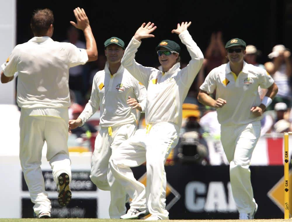 Australia's Steven Smith, center, celebrates with Ryan Harris, left, after Harris got the wicket of England's Alastair Cook, not shown, on the second day of the series-opening Ashes cricket test between England and Australia at the Gabba in Brisbane.