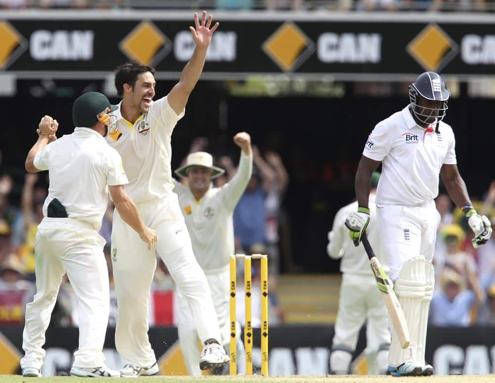 Australia's Mitchell Johnson, center, celebrates with David Warner, left, after he got the wicket of England's Michael Carberry, right, on the second day of the series-opening Ashes cricket test between England and Australia at the Gabba in Brisbane.