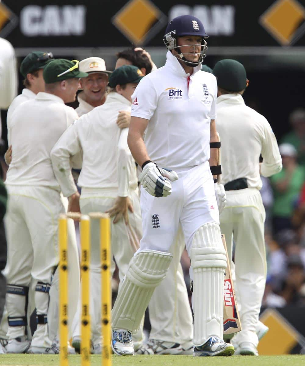 England's Graeme Swann, front, walks back to the dressing room as Australia celebrate his wicket on the second day of the series-opening Ashes cricket test between England and Australia at the Gabba in Brisbane.