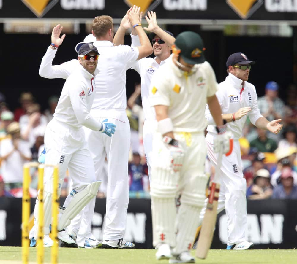 England's cricket team celebrates the wicket of Australia's Chris Rogers, foreground, on the third day of their series-opening Ashes cricket test match at the Gabba in Brisbane.