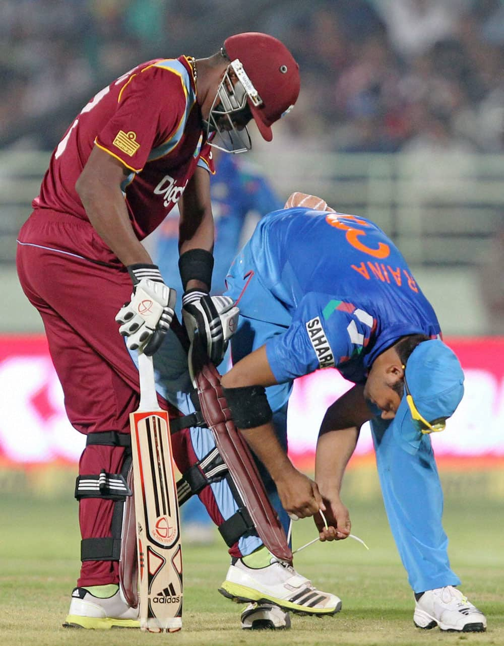 Indian Cricketer Raina ties the shoe laces of Dwayne Bravo during India vs West Indies 2nd ODI Match in Visakhapatnam.