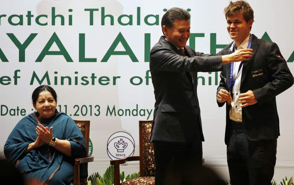 FIDE (World Chess Federation) President Kirsan Ilyumzhinov, center, presents new world chess champion Magnus Carlsen of Norway with a gold medal at the award presentation ceremony of the FIDE World Chess Championship as Chief Minister of Tamil Nadu state J. Jayalalitha, left, claps in Chennai