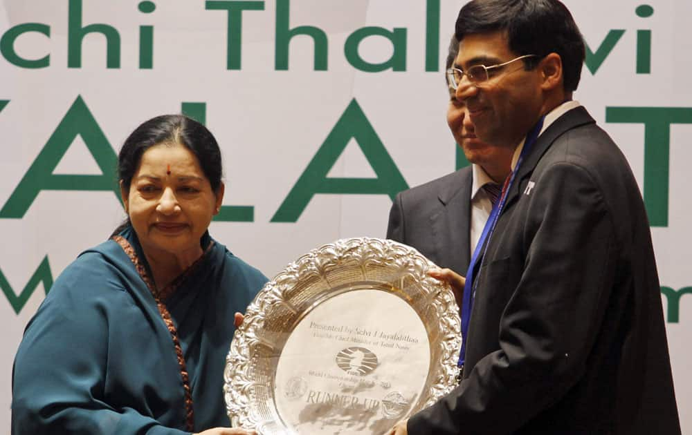 India's Viswanathan Anand, poses with the runner-up trophy presented by Chief Minister of Tamil Nadu state J. Jayalalitha after loosing his title against Norway's Magnus Carlsen in the World Chess Championship, in Chennai.