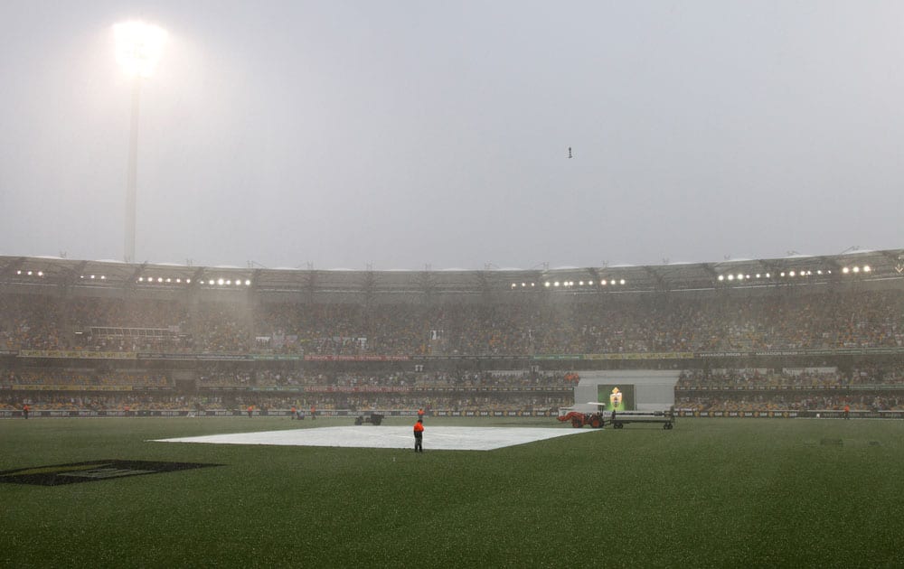 A security guard watches the pitch during a rain storm that interrupted play on the fourth day of the series-opening Ashes cricket test between England and Australia at the Gabba in Brisbane.