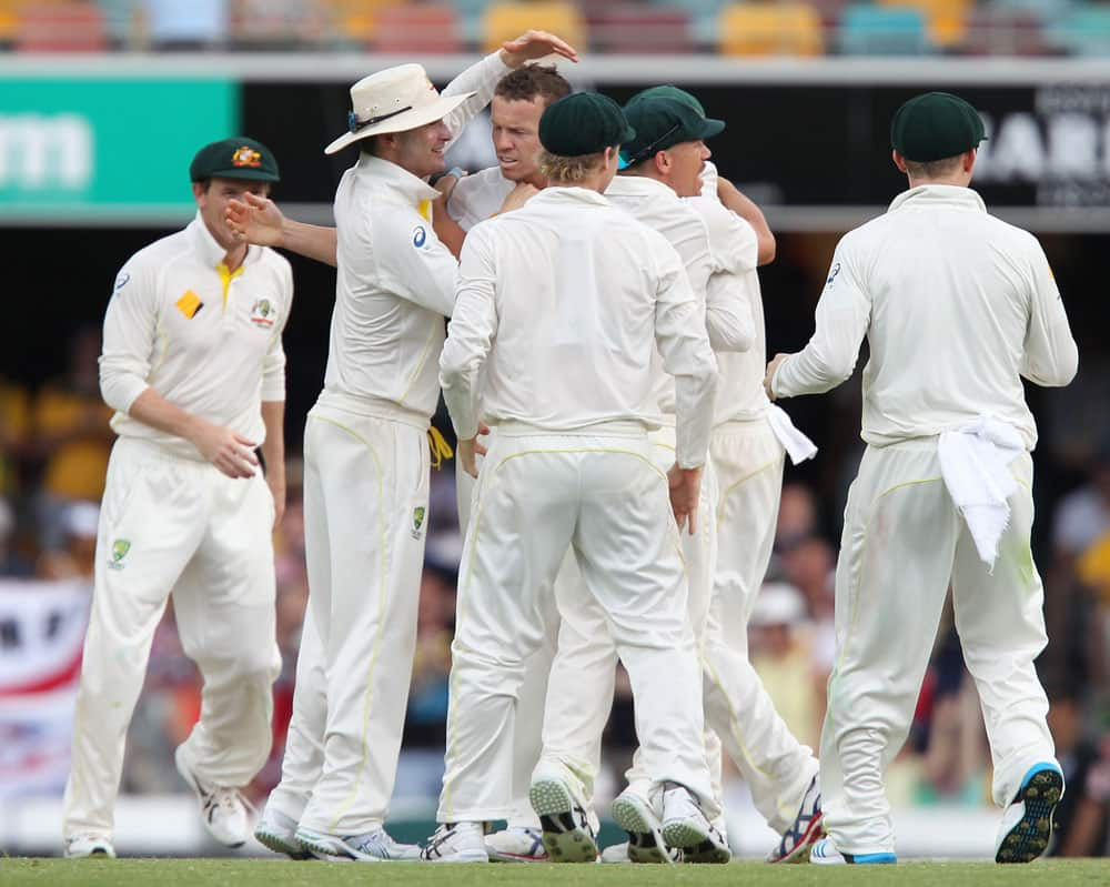 Australia's Peter Siddle, center, without a cap, celebrates with his team after getting the wicket of England's Ian Bell on the fourth day of the series-opening Ashes cricket test between England and Australia at the Gabba in Brisbane.