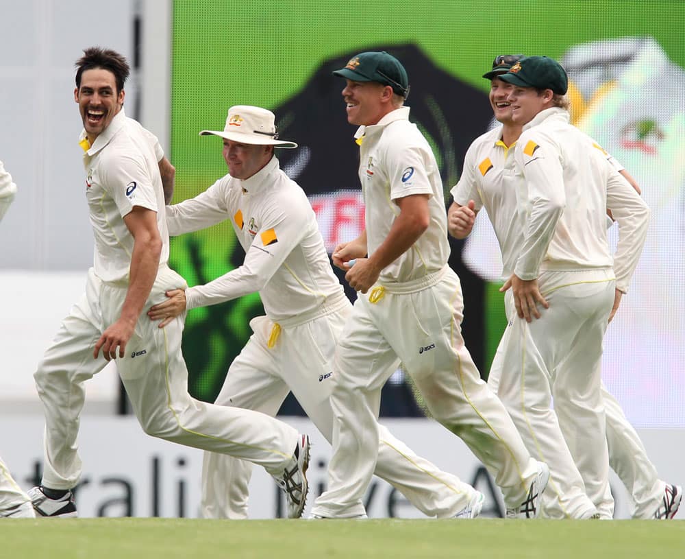 Australia's Mitchell Johnson, Michael Clarke and David Warner, celebrate the wicket of England's Stuart Broad, on the fourth day of the series-opening Ashes cricket test between England and Australia at the Gabba in Brisbane.