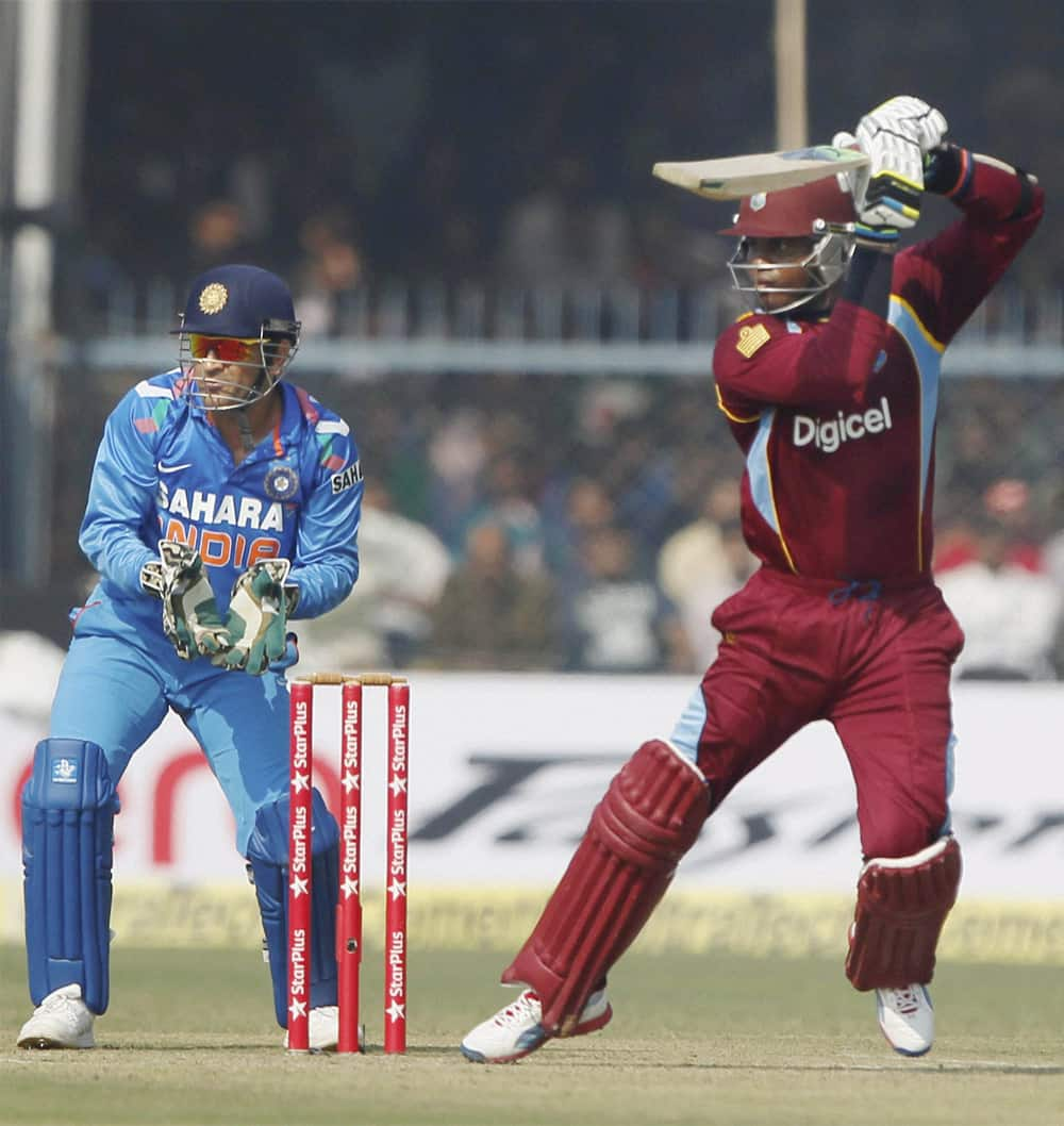 M S Dhoni looks on as West Indies batsman M N Samuels plays a shot during the last ODI match between India and West Indies at Green Park stadium in Kanpur.