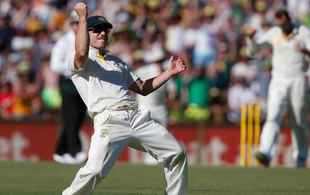 Australia's Dave Warner throws his arms in the air after taking the catch to dismiss England's Alastair Cook for 72 runs on the second day of their Ashes cricket test match in Perth, Australia.