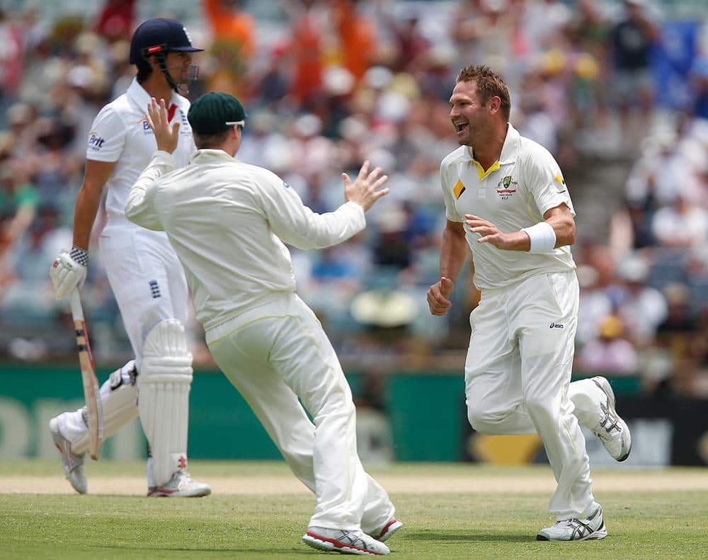 Australia's Ryan Harris, right, celebrates with his teammate, center, after taking the wicket of England's Alastair Cook, left, during England's second innings on the fourth day of their Ashes cricket test match in Perth, Australia.