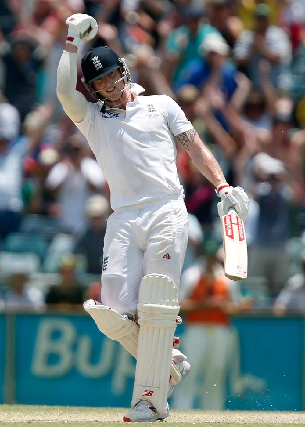 England's Ben Stokes raises his arm after scoring a century on the fifth day of their Ashes cricket test match against Australia in Perth, Australia.