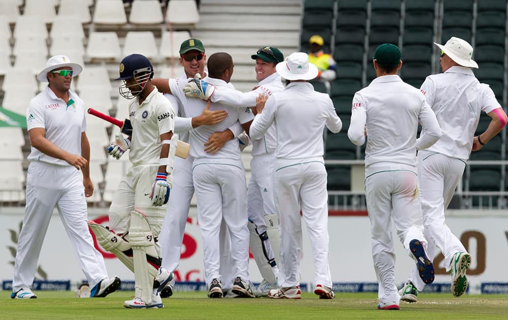Ajinkya Rahane walks back to the pavilion as South Africa's bowler Vernon Philander celebrates his dismissal with teammates during the second day of their cricket test match at Wanderers stadium in Johannesburg, South Africa.