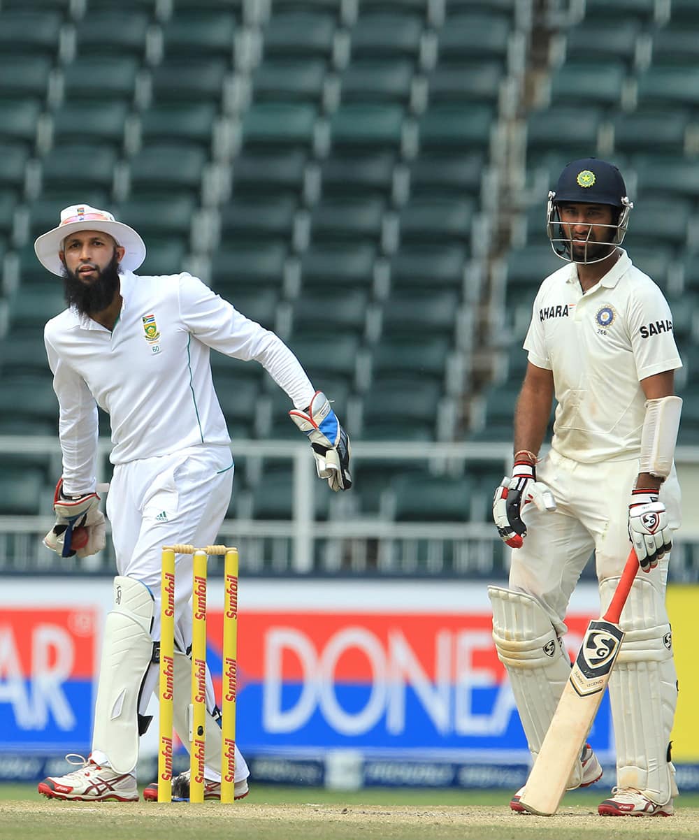 Hashim Amla throws the ball as Cheteshwar Pujara watches during India's 2nd innings on the third day of their cricket test match at Wanderers stadium in Johannesburg, South Africa.