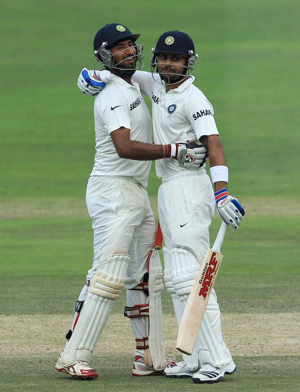 Cheteshwar Pujara, left, is embraced by teammate Virat Kohli, right, after reaching his century during their 2nd innings on the third day of their cricket test match against South Africa at Wanderers stadium in Johannesburg.