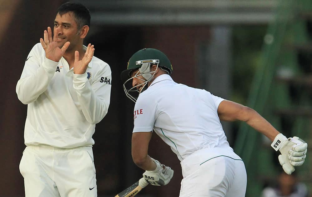 India's captain Mahendra Singh Dhoni, left, avoids colliding with South Africa's batsman Alviro Petersen, right, during South Africa's 2nd innings on the fourth day of their cricket Test match at Wanderers stadium in Johannesburg, South Africa.