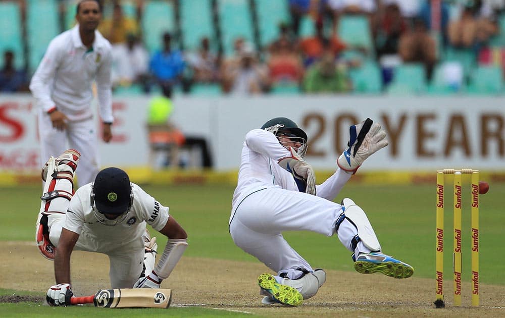 South Africa's wicketkeeper Abraham Benjamin de Villiers, right, attempts a run out against India's batsman Cheteshwar Pujara, left, during first day of their cricket test match at Kingsmead stadium, Durban, South Africa.