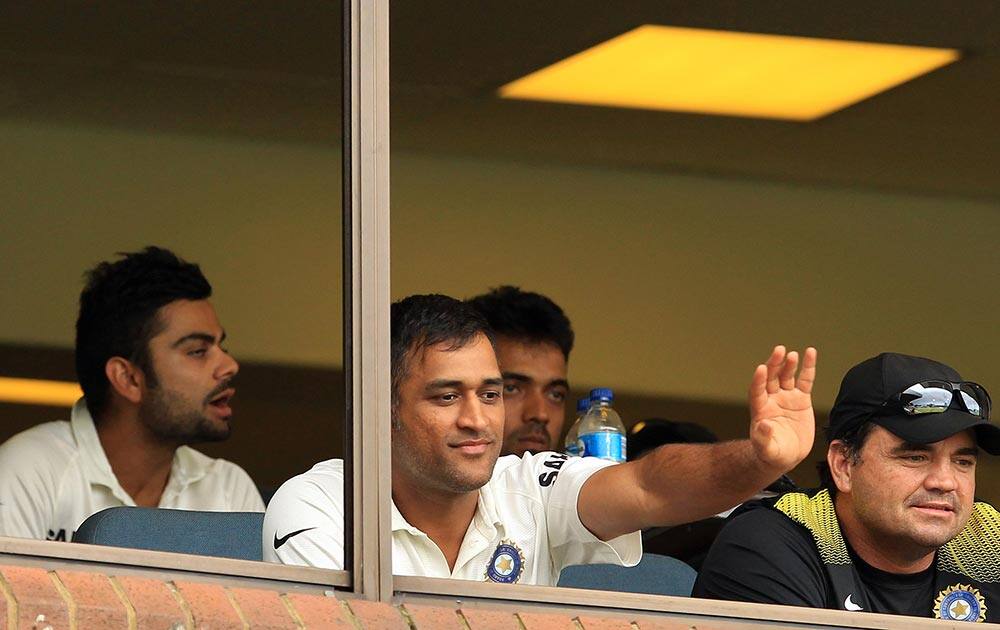 Mahendra Singh Dhoni, center, with teammate India's Virat Kohli, left, waves in the players pavilion as the match is stopped due to bad light during first day of their cricket test match against South Africa at Kingsmead stadium, Durban.