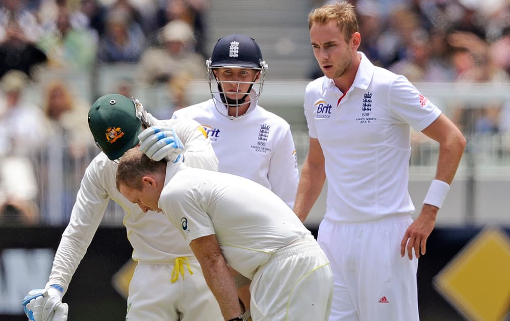 Australia's Chris Rogers is attended to by his captain Michael Clarke as England's Stuart Broad and Joe Root observe after Rogers was struck in the head by a Broad delivery during their Ashes cricket test match at the Melbourne C