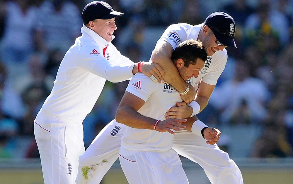 England Tim Bresnan celebrates with teammates James Anderson and Joe Root after taking the wicket of Australia's Mitchell Johnson for 2 runs during their Ashes cricket test match at the Melbourne Cricket Ground in Melbourne, Australia.