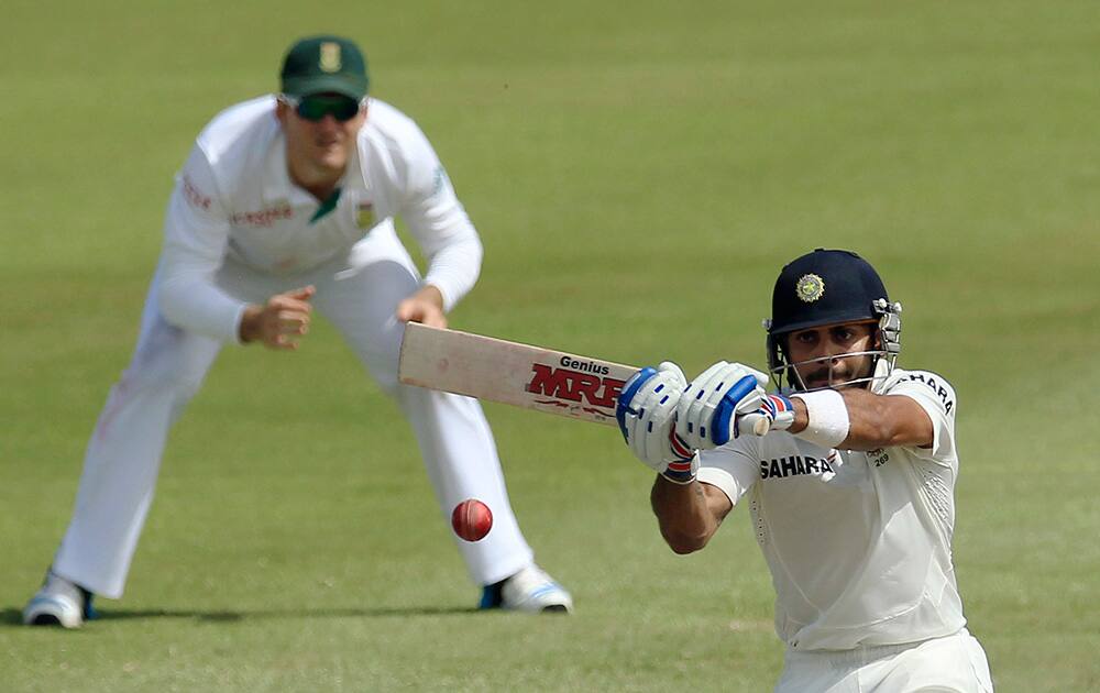 Virat Kohli plays a shot as Graeme Smith watches during second day of their cricket test match at Kingsmead stadium, Durban, South Africa.