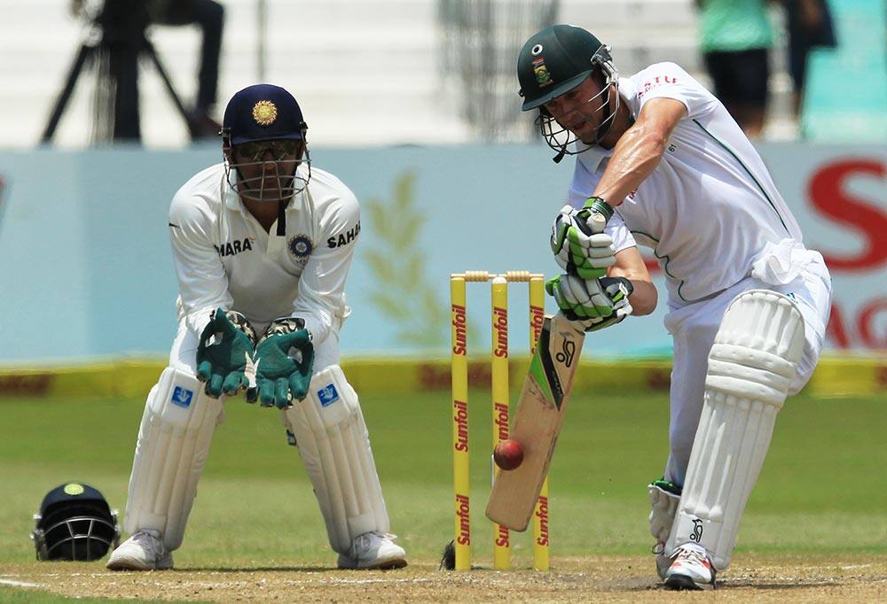 South Africa's batsman Abraham Benjamin de Villiers, right, plays a shot as India's captain Mahendra Singh Dhoni, left, watches, on the third day of their cricket test match at Kingsmead stadium, Durban, South Africa.