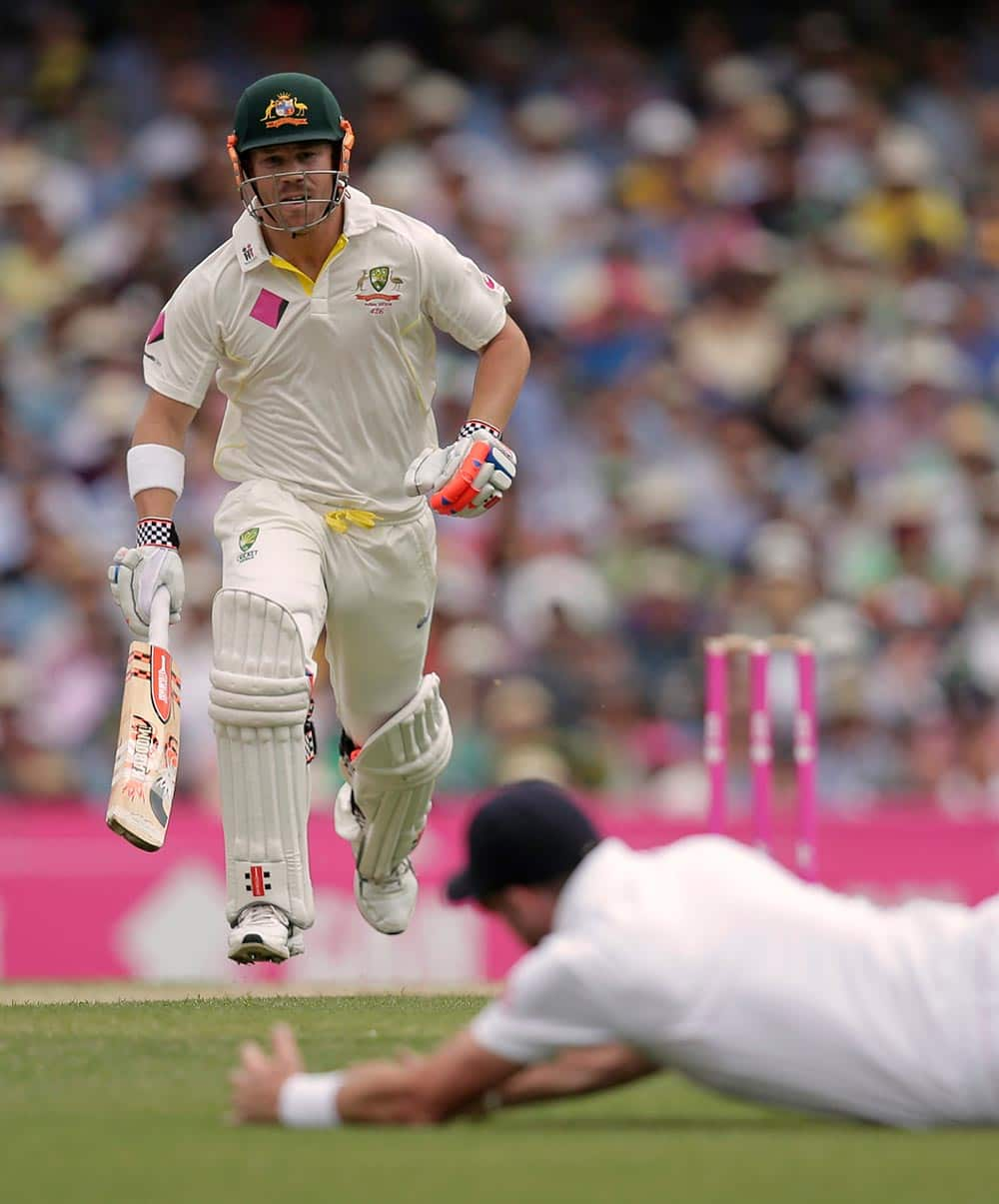 Australia's David Warner, left, makes runs as England's James Anderson dives to attempt a fielding play in their Ashes cricket test match at the Sydney Cricket Ground in Sydney.