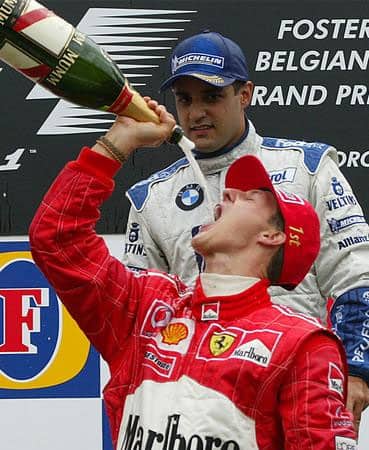 Third placed Juan Pablo Montoya of Colombia looks at German Ferrari driver Michael Schumacher drinking champagne after winning the Belgium Formula One Grand Prix at the Spa-Francorchamps circuit in September 2002.