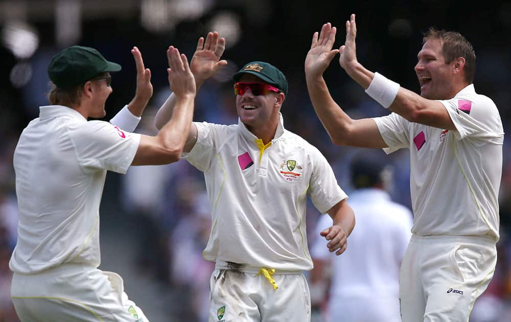 Australia's Shane Watson, left, David Warner, center, and Ryan Harris, right, celebrate after taking the wicket of England's Kevin Pietersen for 3 runs during their Ashes cricket test match at the Sydney Cricket Ground in Sydney.