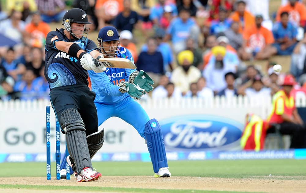New Zealand's Corey Anderson, left, hits a boundary in his innings of 44 off 17 balls in front of India’s MS Dhoni in the second one-day International cricket match at Seddon Park in Hamilton, New Zealand.