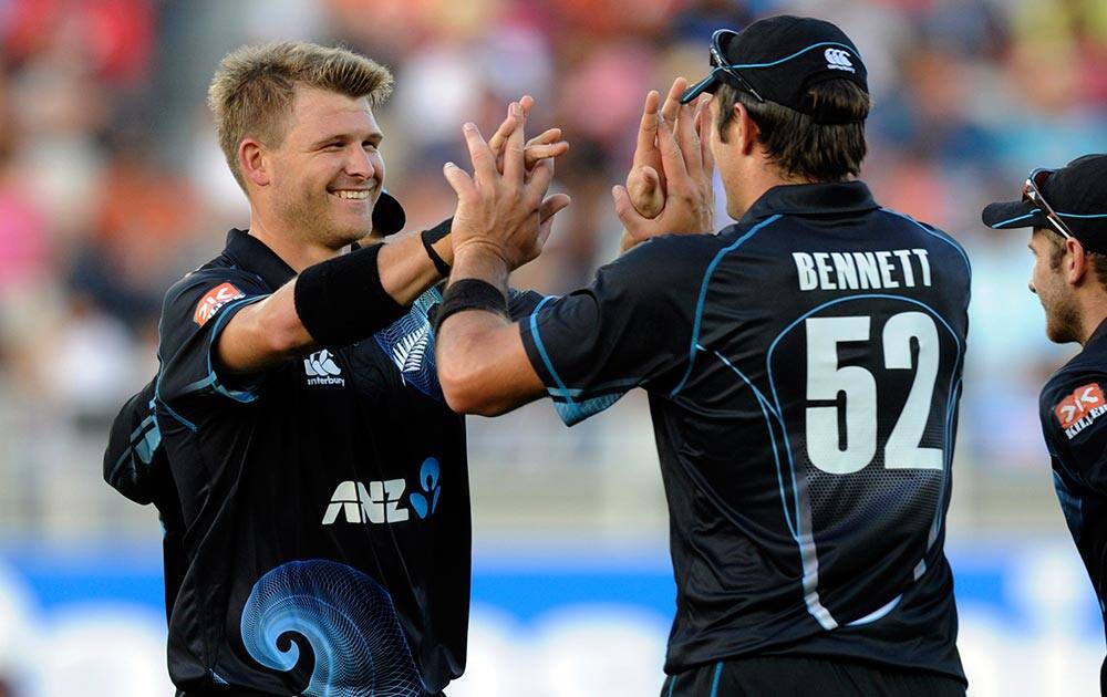 New Zealand's Corey Anderson, left, celebrates with Hamish Bennett after he took the catch off his bowling to dismiss India’s Rohit Sharma for 39 in the third one-day International cricket match at Eden Park in Auckland.