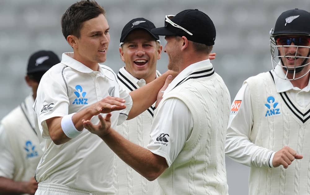 New Zealand’s Trent Boult, left, celebrates with Corey Anderson after dismissing India’s Cheteshwar Pujara for 1 on the second day of the first cricket test at Eden Park in Auckland, New Zealand.