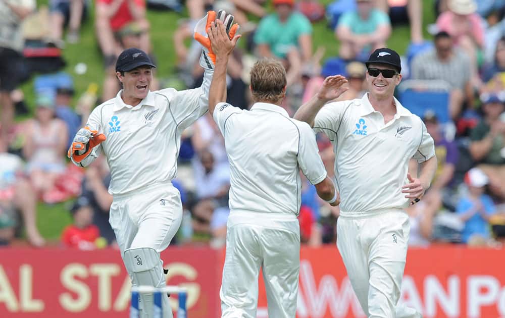 New Zealand’s Neil Wagner, center, celebrates with BJ Watling, left and James Neesham after he dismissed India’s Virat Kohli for 38 on the second day of the second cricket test in Wellington, New Zealand.