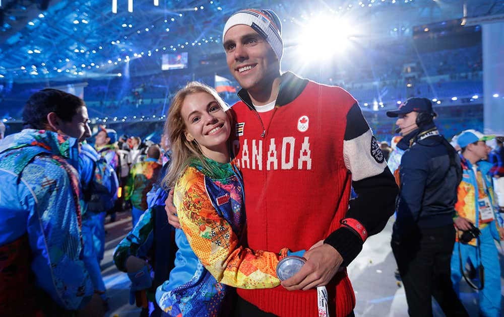 A Canadian athlete, right, poses for a photograph with a volunteer during the closing ceremony of the 2014 Winter Olympics.