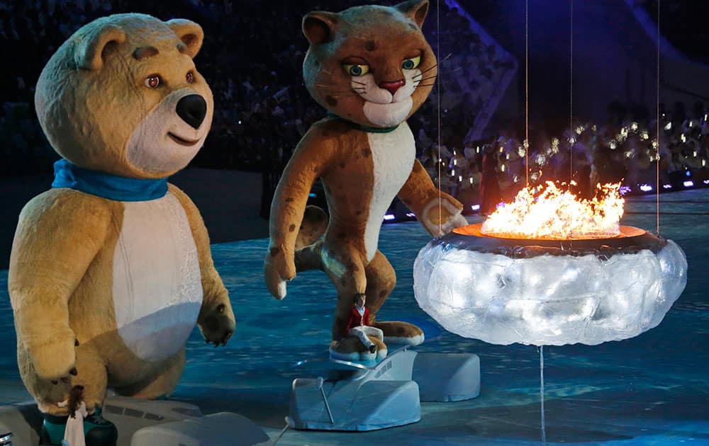 A polar bear and a leopard, mascots of Sochi 2014, approach a flame representing the burning Olympic cauldron, during the closing ceremony of the 2014 Winter Olympics.