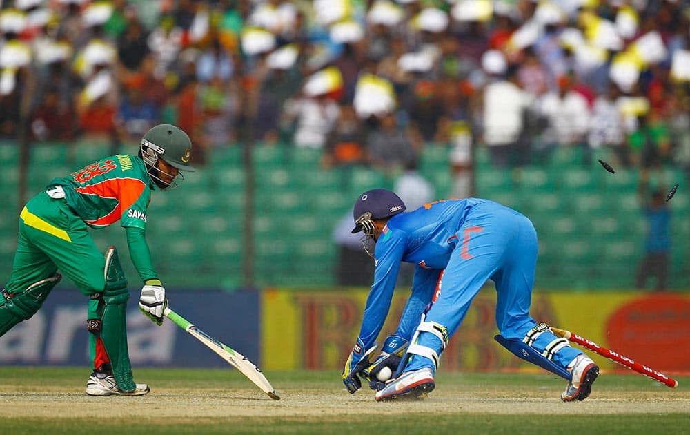 India’s Dinesh Karthik, right, successfully dislodges the bails to dismiss Bangladeshi Mominul Haque during the Asia Cup one-day international cricket tournament in Fatullah, near Dhaka, Bangladesh.