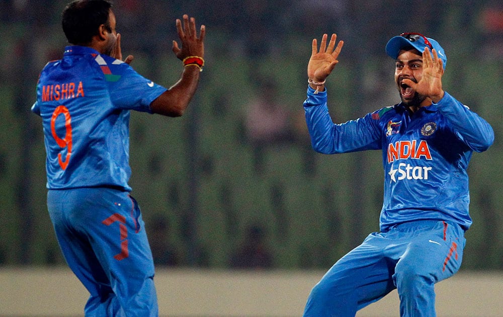 Amit Mishra, left, celebrates with teammate Virat Kohli after taking the wicket of Pakistan’s Ahmed Shehzad during the Asia Cup one-day international cricket tournament in Dhaka.