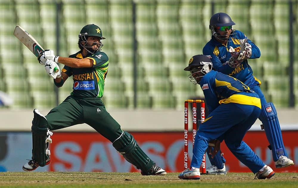 Pakistan’s Fawad Alam, left, plays a shot in front of Sri Lankan wicketkeeper Kumar Sangakkara, right, and a teammate during their Asia Cup final cricket match in Dhaka, Bangladesh.