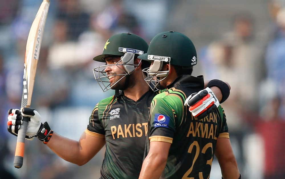 Pakistan's batsman Umar Akmal, left, raises his bat as he hugs teammate and his brother Kamran Akmal after scoring a half century during their ICC Twenty20 Cricket World Cup match against Australia in Dhaka.