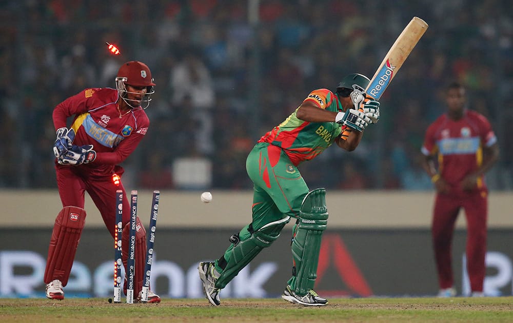 Bangladesh batsman Shakib Al Hasan, center, is bowled out by West Indies' bowler Krishmar Santokie during their ICC Twenty20 Cricket World Cup match in Dhaka, Bangladesh.