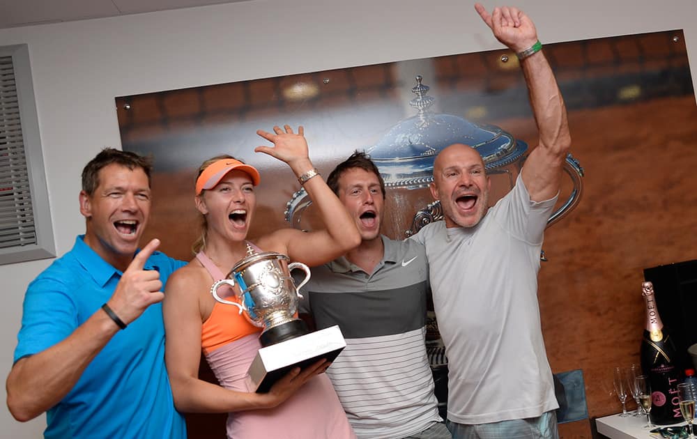 Russia's Maria Sharapova holds the trophy as she poses for a portrait with her coaches Sven Groeneveld of The Netherlands, left in blue, and Jerome Bianchi of France, far right, in the locker room after winning the final of the French Open tennis tournament.