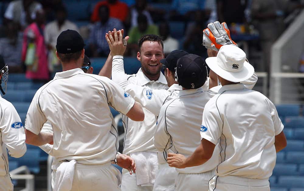 New Zealand's bowler Mark Craig, center facing camera, celebrates with teammates after taking the wicket of West Indies Kirk Edwards who was caught by New Zealand's Ross Taylor for a duck during the third day of their first cricket Test match in Kingston, Jamaica.