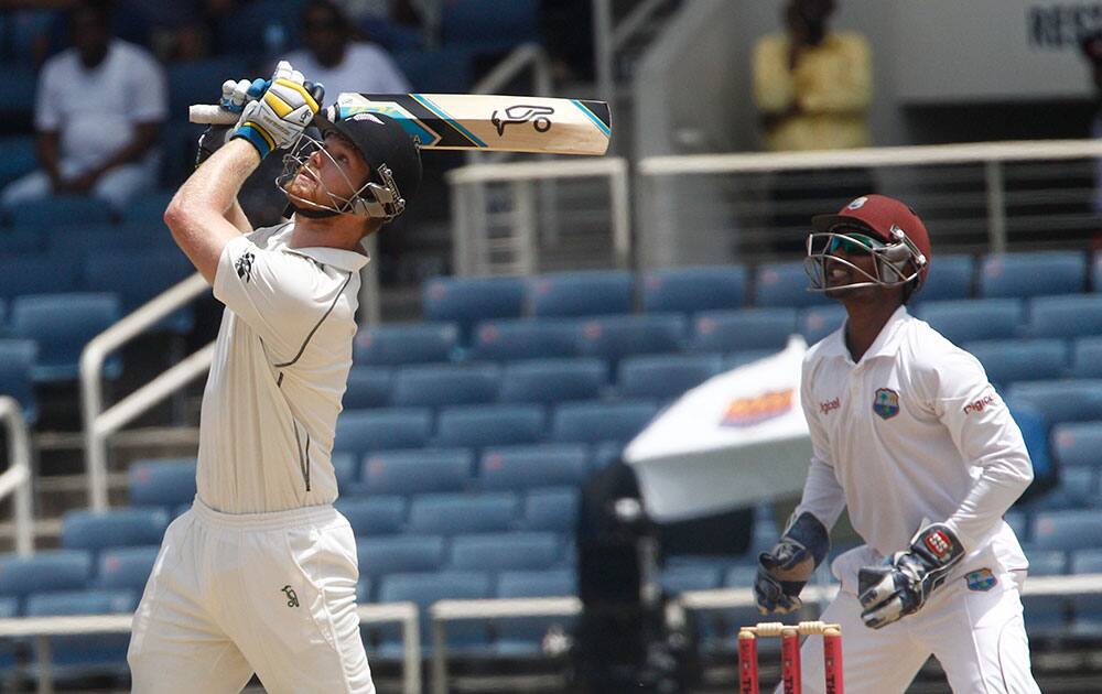 New Zealand's batsman Jimmy Neesham, left, bats to be caught out by West Indies' Kraigg Brathwaite, unseen, for 20 runs as wicket keeper and captain Denesh Ramdin looks on during the second innings on the fourth day of their first cricket Test match in Kingston, Jamaica.